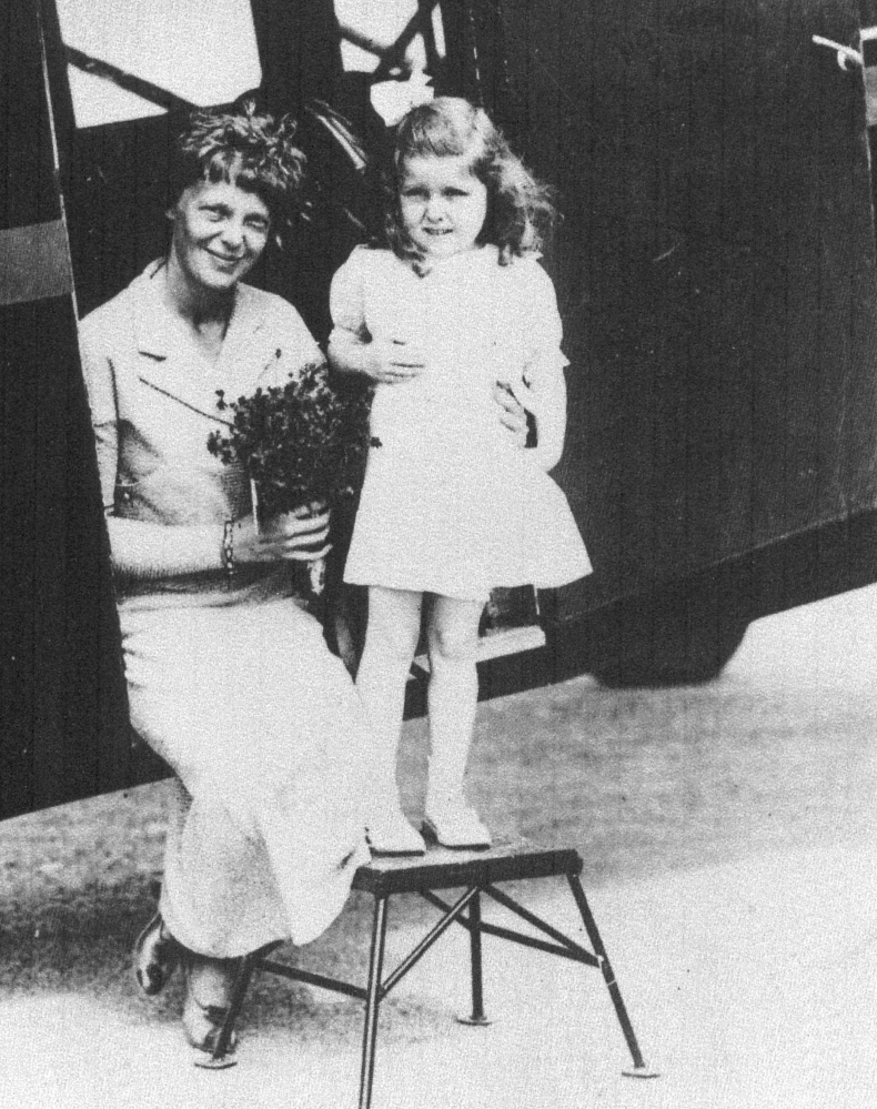 Amelia Earhart receives flowers from 5-year old Gladys Chase of Augusta on Aug. 14, 1934, at  the Augusta airport. The two were photographed in the doorway of a Boston & Maine Airways Stinson plane.