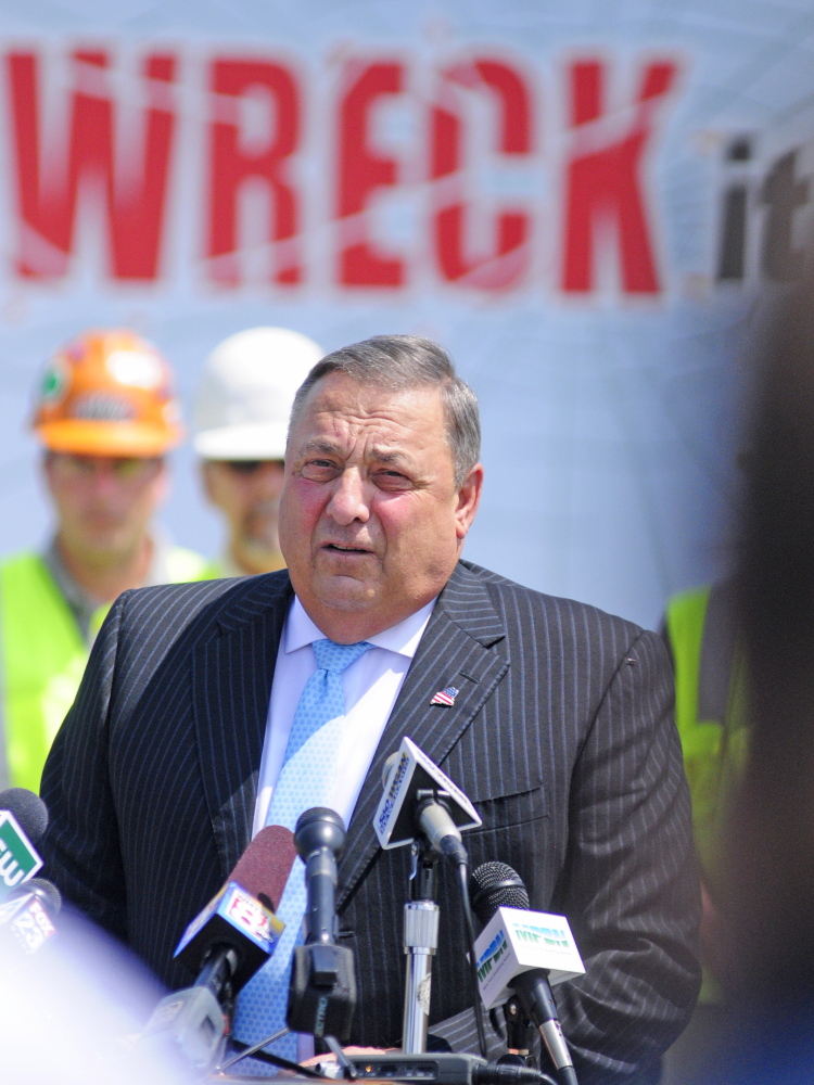 Gov. Paul LePage stands in front of a truck with the words “One text or call could wreck it all,” as he talks about distracted driving on Tuesday during a news conference in the parking lot outside State Police headquarters in Augusta.