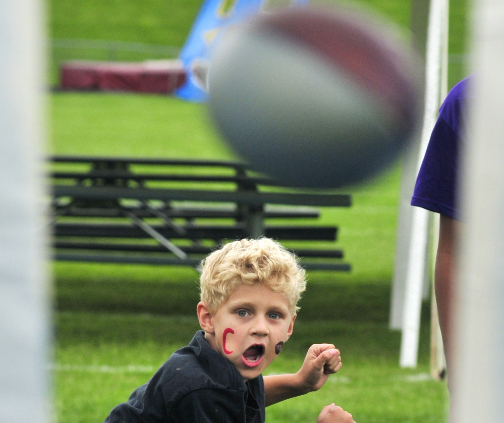 Parker Morin throws a toy football through a hole in a tarp to win a prize during a fundraiser on Saturday at Cony High’s Alumni Field. Alison Lucas, mother of former Cony quarterback Ben Lucas, was recently diagnosed with cancer.