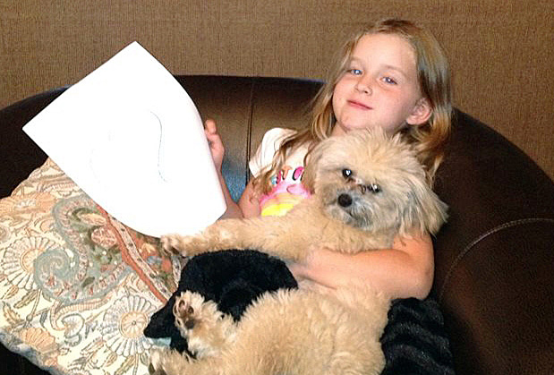 Coral Grimmett, 5, relaxes with her dog Harry at their home in Edmund, Okla., im in this photo provided by  Danel Grimmett. The Associated Press