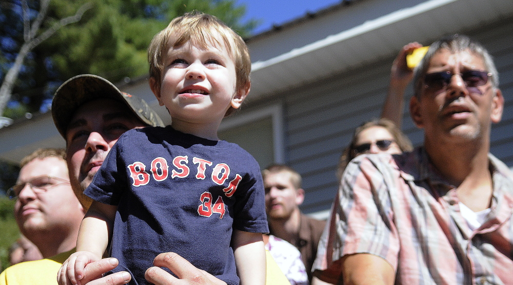 Zackary Hafner, 1, in the arms of his father, Miles, watches the demolition derby at the Litchfield Fair on Sunday.