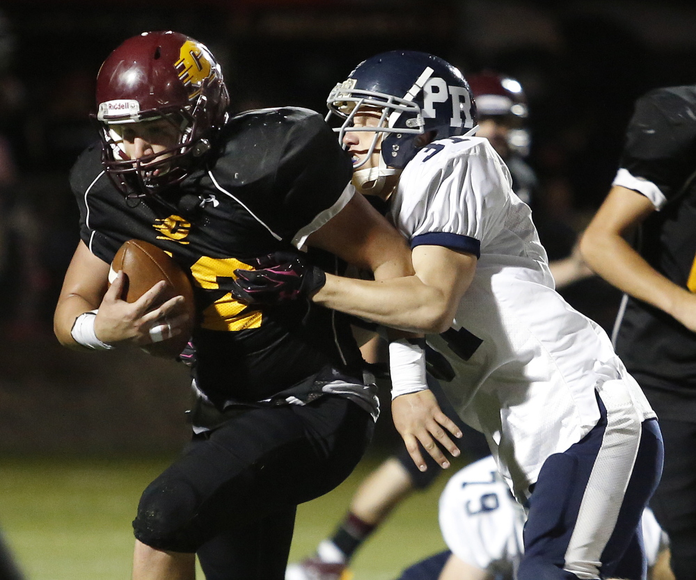 Cape Elizabeth running back Christian Lavallee breaks through the tackle of Poland’s Andrew Demers during the second quarter Friday night. The Capers improved to 2-0 with a 32-29 win.