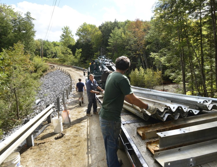 Ray Clark and Derek Alves  of Main Line Fence install a guard rail Monday along the rebuilt private road leading to two homes in Freeport. Nearly two dozen businesses donated labor, materials or money to help the homeowners after a storm washed out part of their access road.was washed out during a storm.