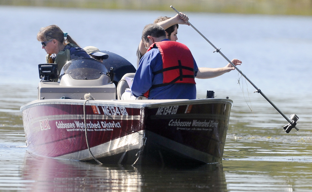 A crew from the Cobbossee Watershed District search above and below the surface of Annabessacook Lake in Winthrop on Wednesday for invasive variable water milfoil.