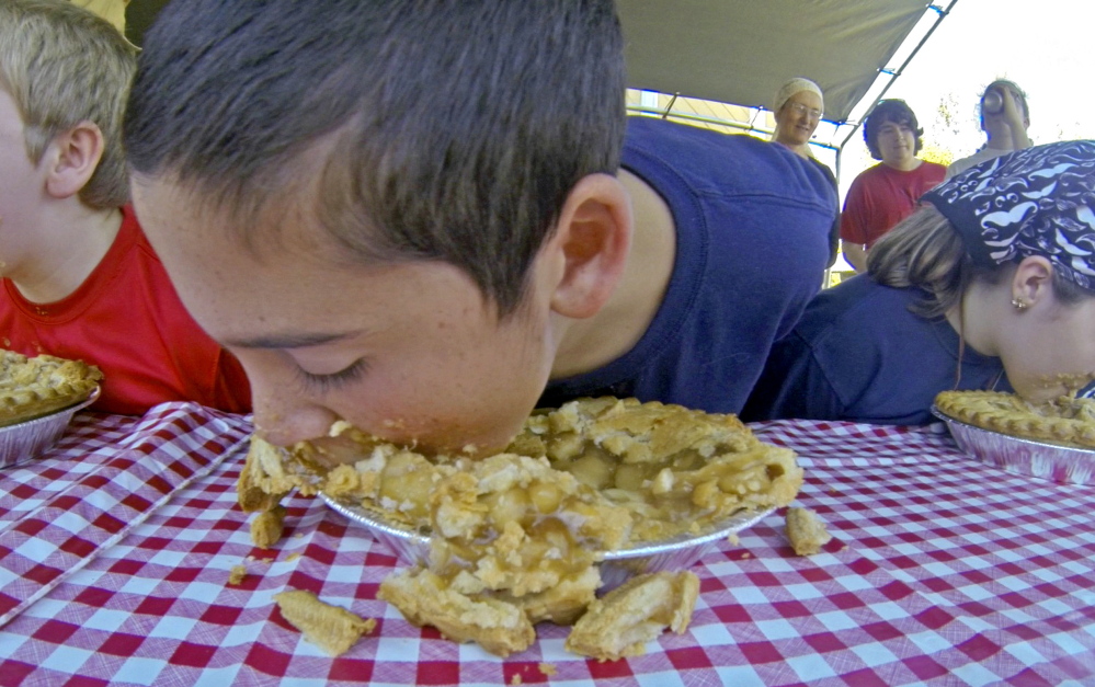 Ethan Larabee, center, is flanked by Max Hill, left, and Emmaleigh Fish as they compete in an apple pie-eating contest on Saturday during the Monmouth AppleFest.