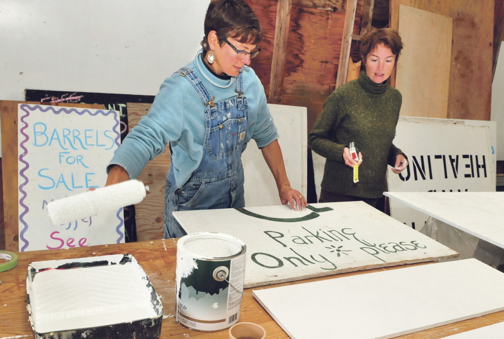 Volunteers Thia Embers, left, and Sarah Tewhey paint signs to be placed around the site of the three-day Common Ground Country Fair that begins Friday in Unity.