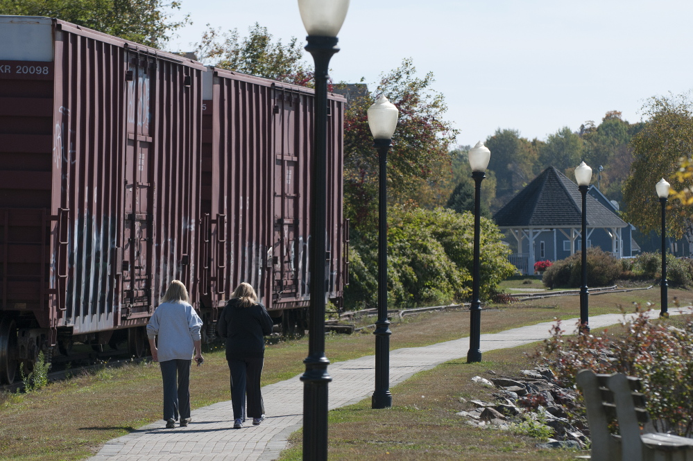 Pam Chaisson, left and Karen Wardwell, right, walk along Bucksport’s waterfront on Thursday. The mill, which anchors one end of the riverfront walkway, names high energy costs as a major factor in the shutdown, though it plans to keep running its adjacent power plant to sell electricity back to the grid.