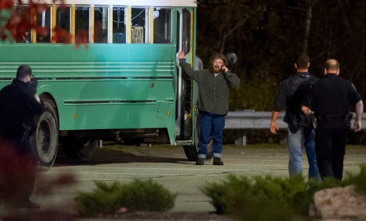 A man shouts to police as one officer has a rifle trained on him and others approach him around 8:35 Monday night in the parking lot outside the Target store in South Portland. The man ran back on the bus before surrendering to police minutes later.