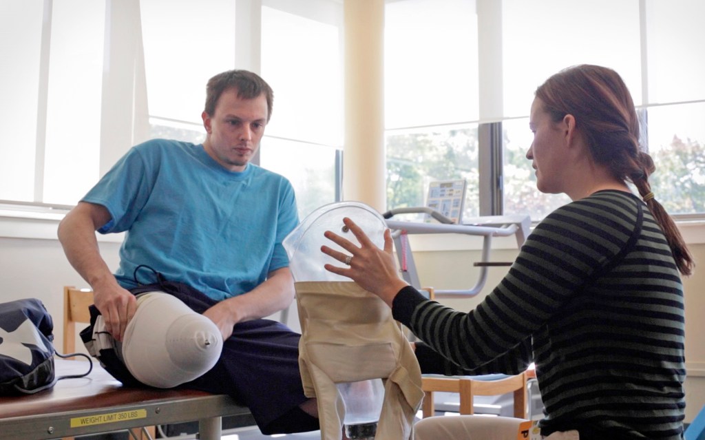 Tim Niles, left, learns how to wear his prosthetic leg during a session last month with physical therapist Lindsay Dunstan at the New England Rehabilitation Hospital in Portland. “Nothing is going to stop me,” says Niles, who is a former Old Town High School sports star. Amelia Kunhardt/Staff Photographer