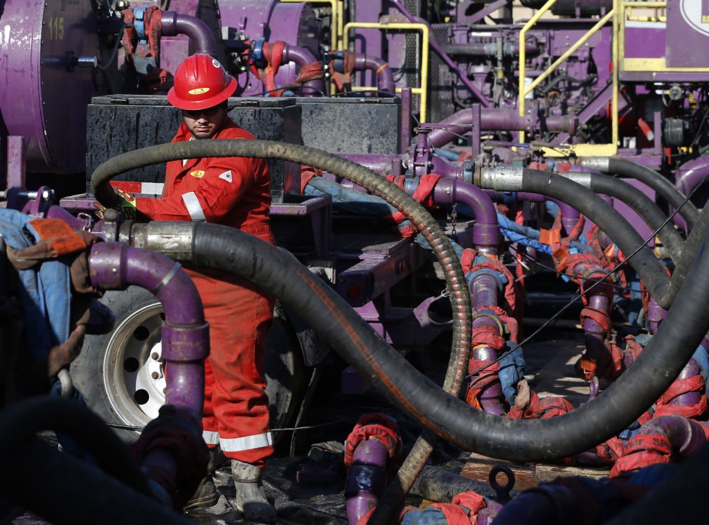 A worker adjusts hoses during a hydraulic fracturing operation at an Encana Corp. oil well, near Mead, Colo. The United States depends less on imported oil now, partly because of such operations.