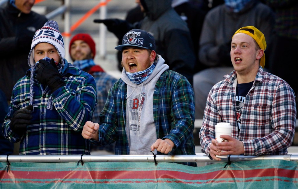 Maine fans cheer during a college football game between Maine and New Hampshire on Saturday in Orono. Organizers hoped to boost attendance at the chilly event by giving away bandannas, below, in a shot at setting a Guinness world record. Photos by Robert F. Bukaty/The Associated Press 
