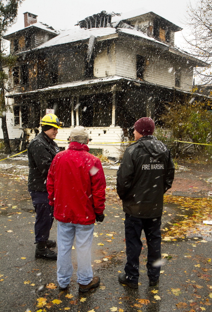 Members of the State Fire Marshals Office talk Sunday with Stephen McCausland, center, spokesman for the state Department of Public Safety, outside 20-24 Noyes St.