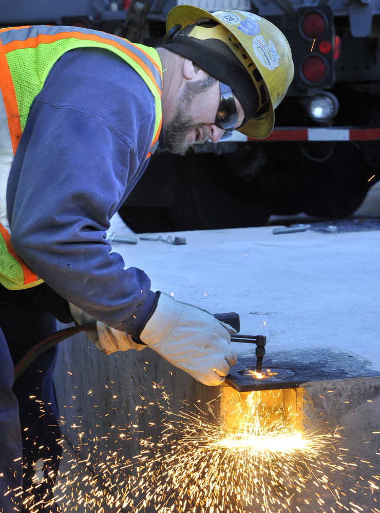 Mike Labbe cuts holes for bolts that will hold the 8-foot-tall sculpture in place.