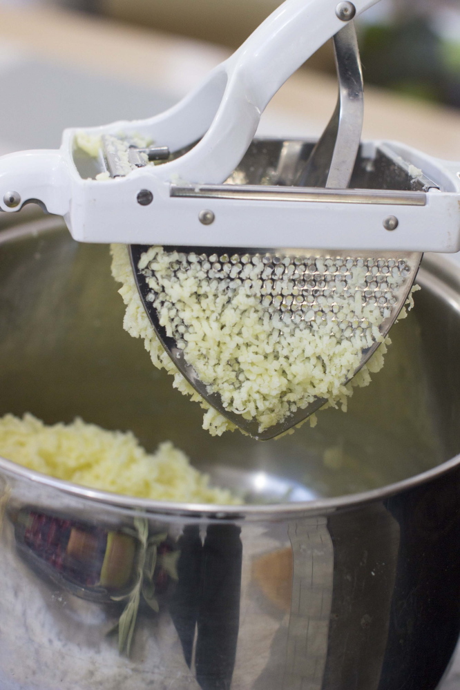 Boiled potatoes going through a ricer for a creamy mashed potatoes recipe in Concord, N.H. A ricer makes a great tool to mash potatoes, because the quickness with which a ricer forces the cooked potato through its holes keeps the agitation of the starch to a minimum.