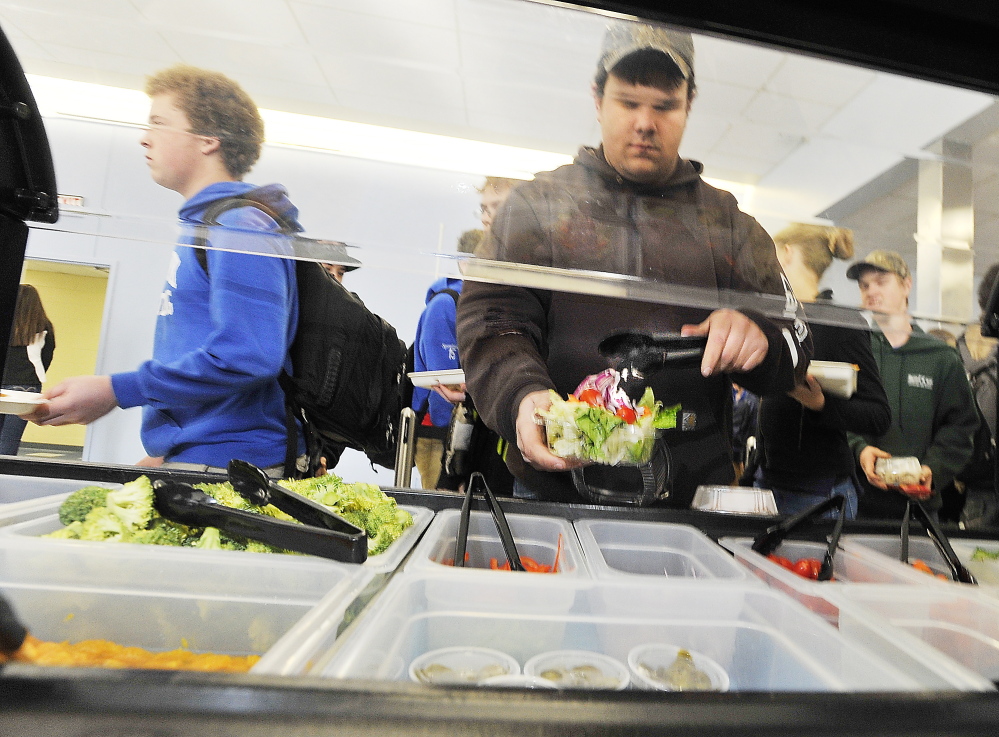 Senior Kenny Davis adds a cherry tomato to his salad Kennebunk High School's cafeteria.