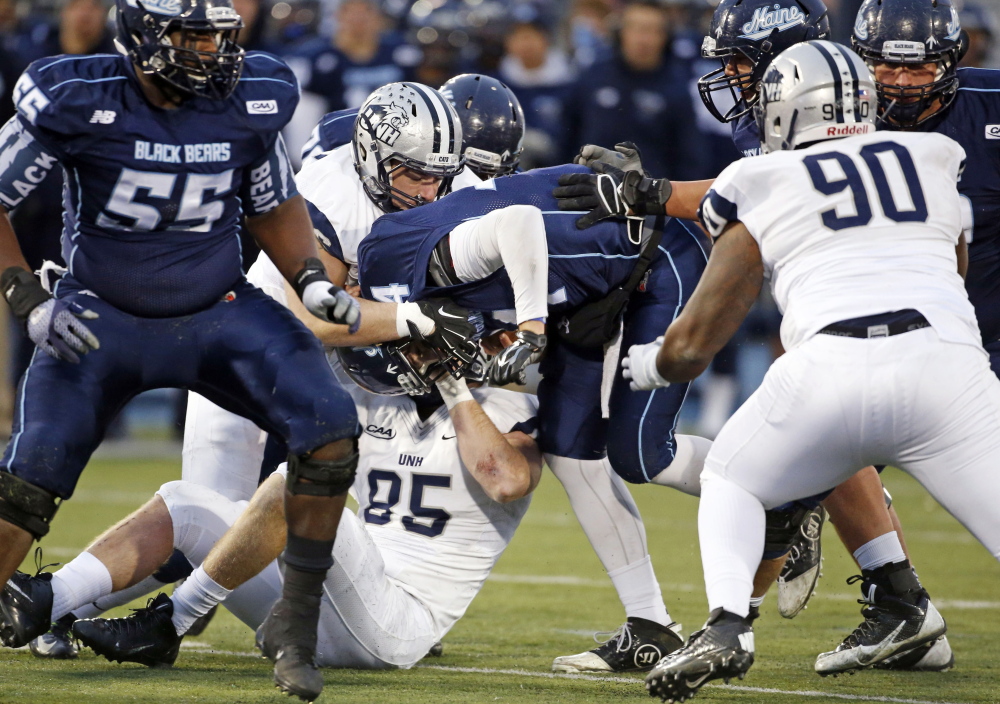 Maine quarterback Drew Belcher (14) gets sacked by New Hampshire's Cody Muller (96) and defensive end Brian Ciccone (85) during the first half Saturday  in Orono.
