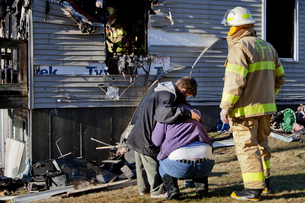 Greg Ballou, 26, of Freeport comforts his wife, Ardelle Ballou, along with Freeport fire chaplain Sandy Williams, after the Ballous lost their home on Varney Road to a fire Saturday afternoon. 