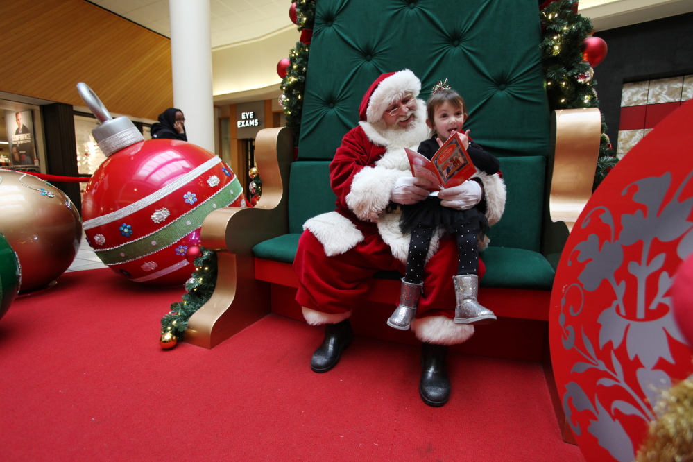 Good time management allows Santa to read to 4-year-old Paige Brooks at the Maine Mall even as the big day approaches in 2014.