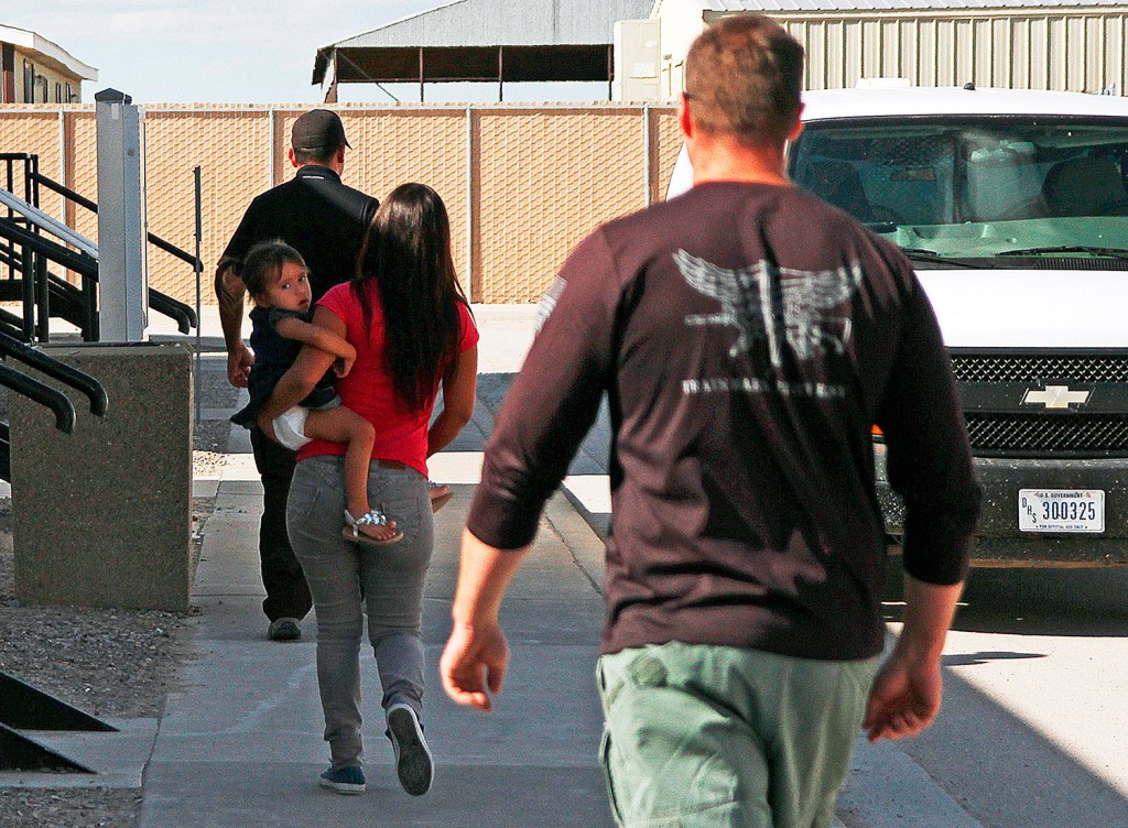 A woman and child are escorted to a van by detention facility guards inside the Artesia Family Residential Center, a federal detention facility for undocumented immigrant mothers and children in Artesia, N.M.