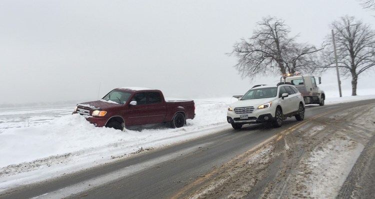 A tow truck prepares to pull out a pickup truck that slid into a snowbank on Baxter Boulevard in Portland Friday morning. 