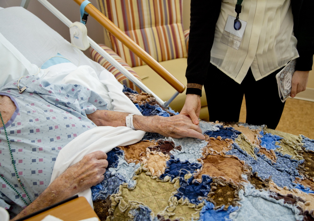 Caitlyn Farrell, a University of New England medical student, holds hands with Selden “Bud” Crocker on Jan. 31 at Gosnell Memorial Hospice House in Scarborough.