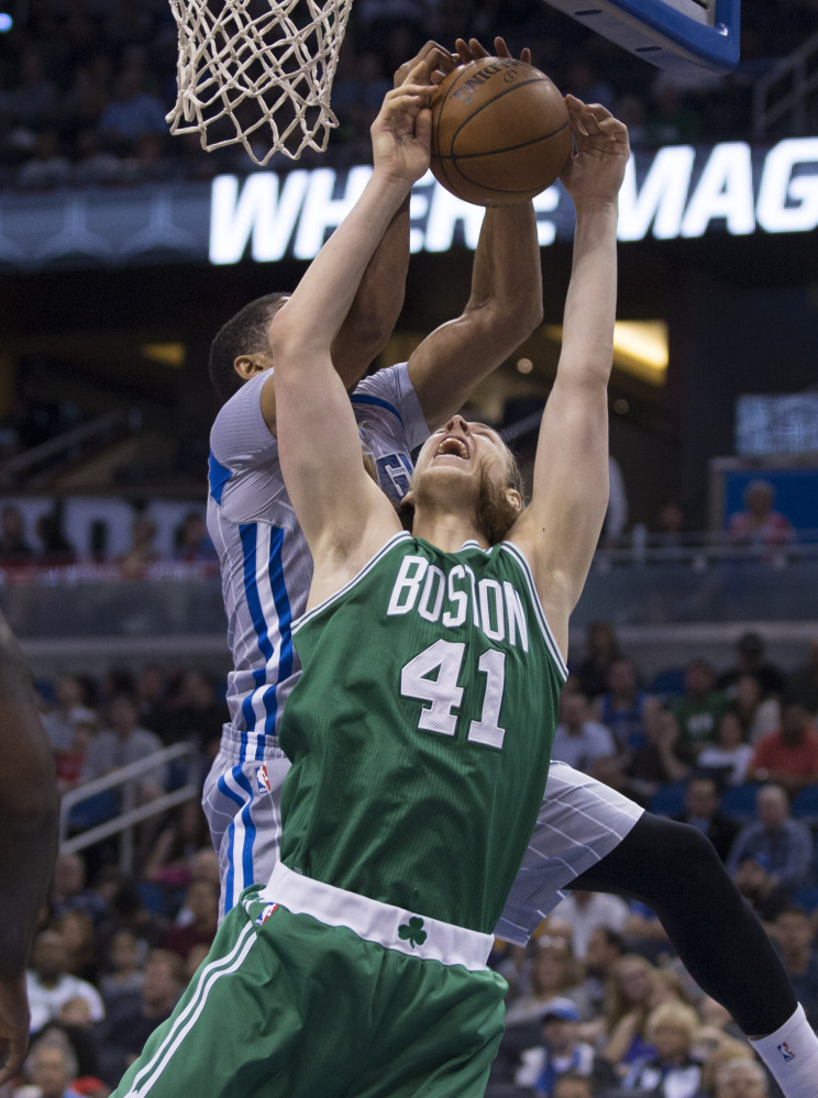Orlando’s Tobias Harris, back, blocks a shot by Boston’s Kelly Olynyk during the Magic’s 103-98 win Sunday in Orlando.