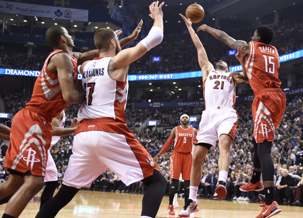 Houston’s Clint Capela, right, and Toronto’s Greivis Vasquez fight for the ball during the first half of a 99-96 win by the Raptors at Toronto on Monday.