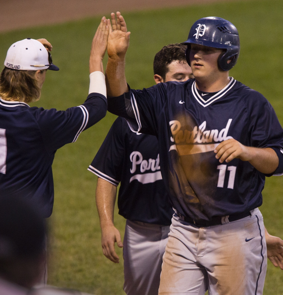 Portland’s Ryan Ruhlin is congratulated by teammates after crossing the plate with the tying run in the fifth inning against Cheverus in an SMAA baseball game on Tuesday.