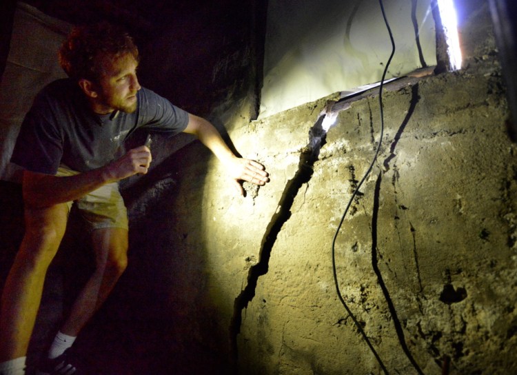 Brent Adler, who with his business partner Liv Chase owns the apartment building at 48 Hancock St., illuminates cracks that formed in the structure’s foundation because of work being done at Seaport Lofts in Portland’s East End. The city says the developers may resume work as long as they comply with four recommendations in an engineering report.