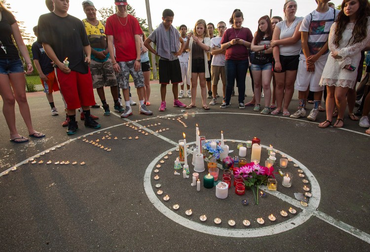 Mourners gather on a public basketball court in downtown Westbrook on Tuesday evening for a candlelight vigil for Treyjon Arsenault.