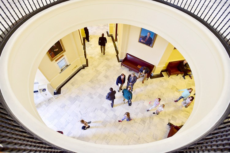 State legislators confer after the daily session as schoolchildren walk by in a tour of the State House on Friday. Republican legislators have submitted their own tax reform plan.