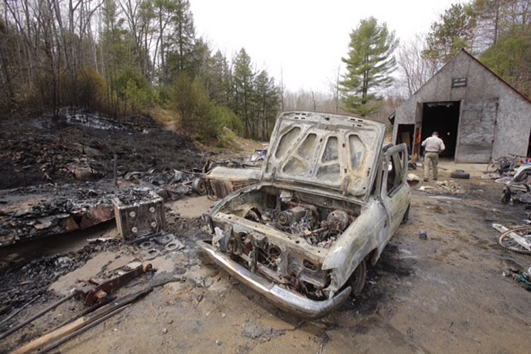 Matthew Bennett of the Maine Forest Service examines the scene of a fire at 183 South Bridgton Road in Bridgton on Tuesday. Jesse Alan, who lives at the address, said he had had a fire on Friday to burn some scrap wood. Tuesday morning, after putting his 2-year-old down for a nap, he heard crackling sounds and saw the fire outside. He grabbed his son, left the house and called 911. Alan lost a truck and a camper in the fire but his mobile home was spared. Gregory Rec / Staff Photographer