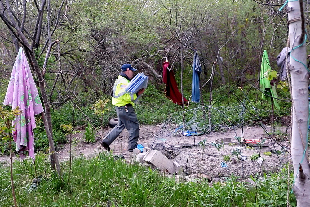 Roger Goodoak carries an armful of tarps last month as he approaches a camp where a homeless man lives in the woods off a shopping center in Portland. Goodoak, a veteran who was once homeless himself, is the founder of the Maine Homeless Veterans Alliance.