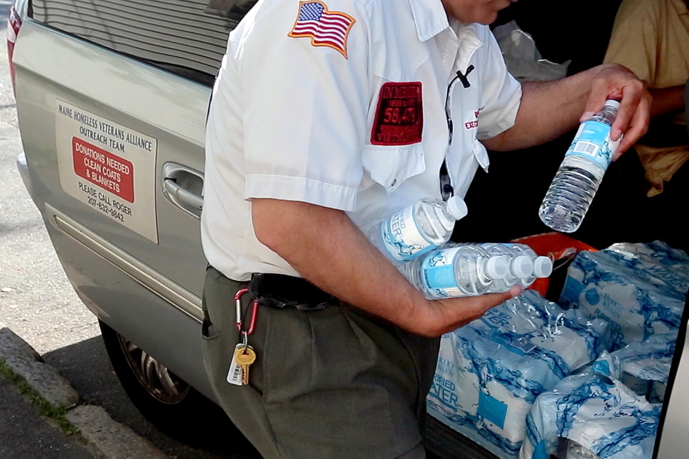 Goodoak fills his arms with bottles of water to hand out in front of the Oxford Street Shelter. Gabe Souza/Staff Photographer