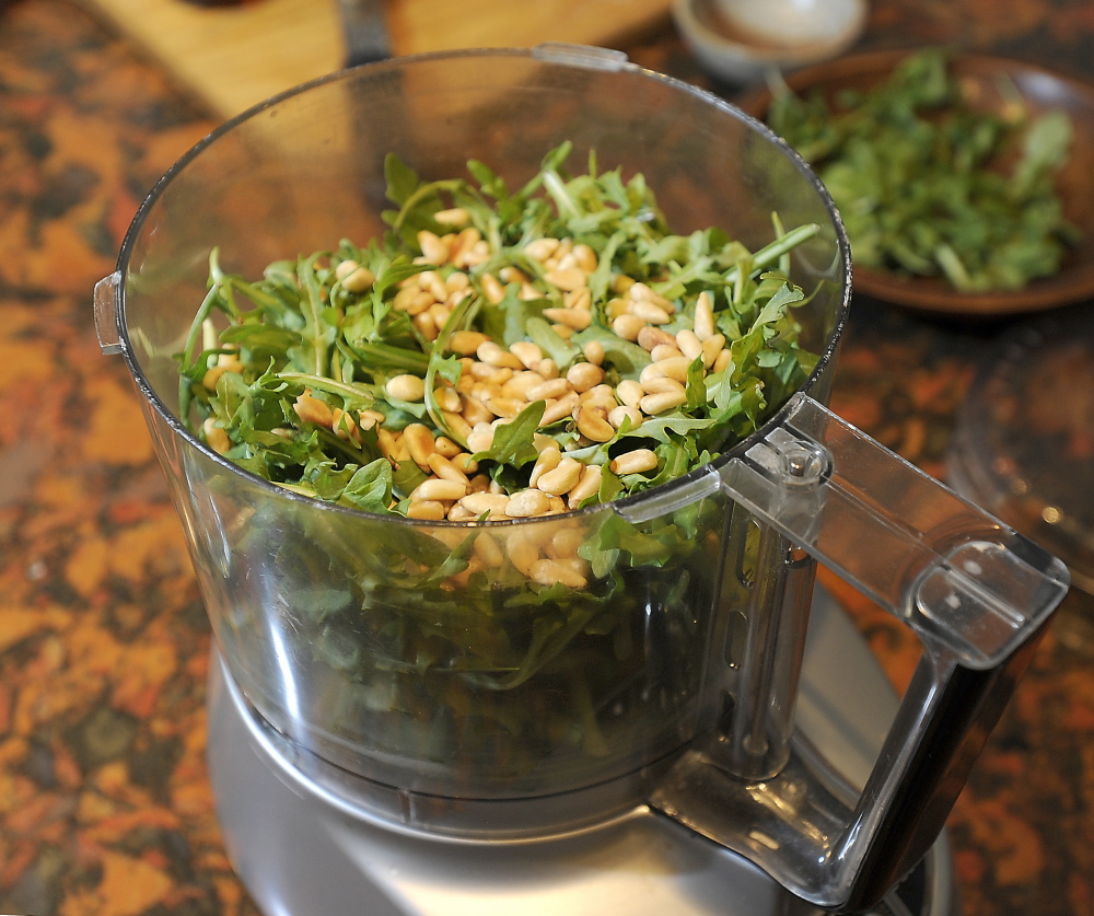 Garlic scapes, arugula and pine nuts ready for pulsing. Scapes act like scallions in the kitchen but taste like sweet garlic.