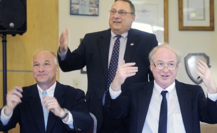 University of Maine Chancellor James Page, right, and Maine Community College System interim President Derek Langhauser and Gov. Paul LePage ask students to join them Monday in applauding the signing of an agreement to expedite the transfer of academic credits between the higher education systems. 