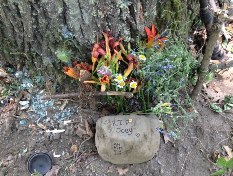 A memorial to Joseph Knox is seen Monday amid glass and car parts at the bottom of a tree after a crash in Vassalboro that killed Knox and Ronald Willey.