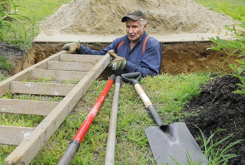 Litchfield Plains Cemetery caretaker Donald Vannah climbs out of a grave he dug by hand at the cemetery. Each plot takes up to five hours to excavate, he said.