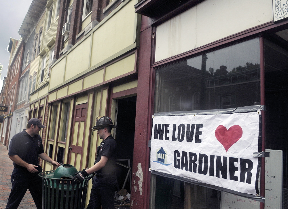 Gardiner firefighters replace a trash can blocking an entrance to 235 Water St. on Sunday after searching for tools lost in the blaze that destroyed the structure last Thursday.