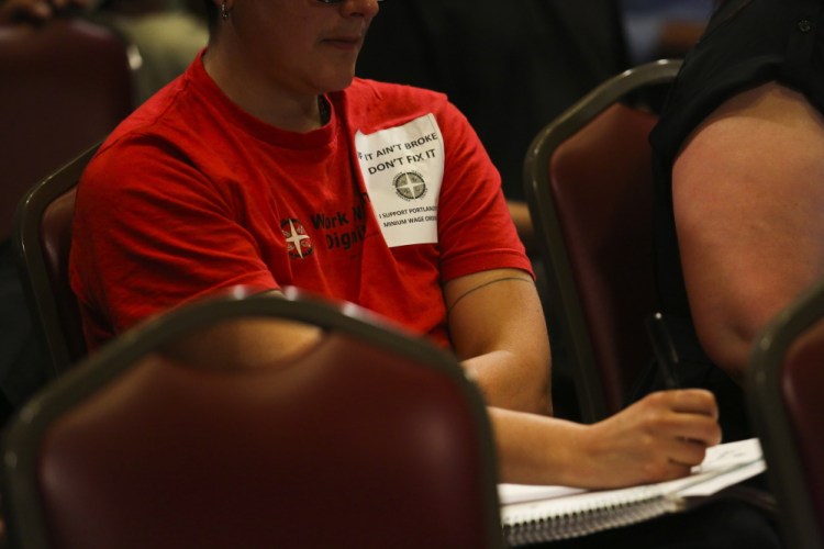 Drew Christopher Joy wears a sticker in support of maintaining the recently passed minimum wage ordinance, which includes tipped workers, at the City Council meeting in Portland Monday.