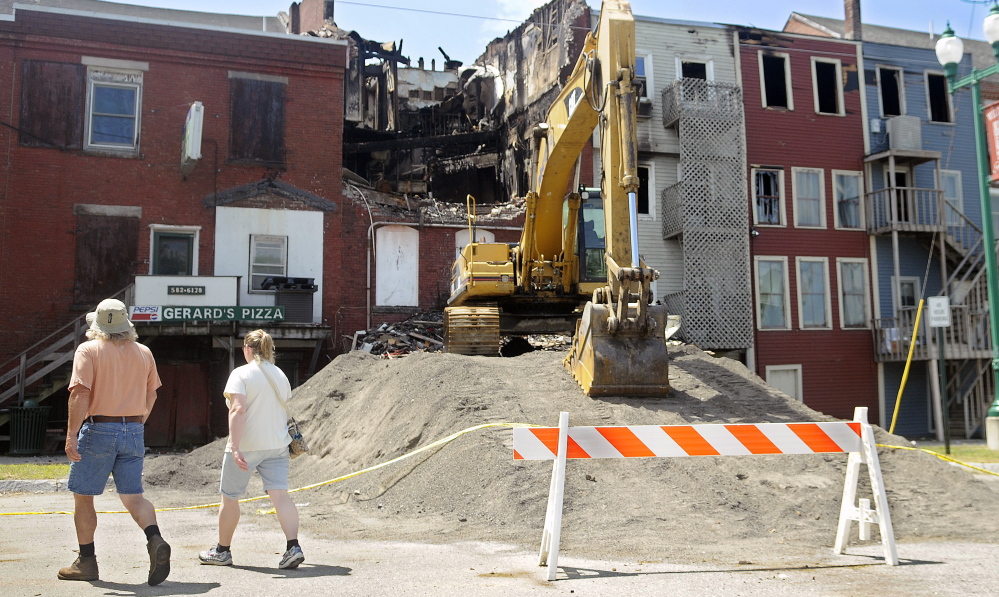 People walk along Water Street in Gardiner on Monday, where a July 16 fire badly damaged four buildings and injured four people, including three firefighters who were hit by bricks when a building partially collapsed.