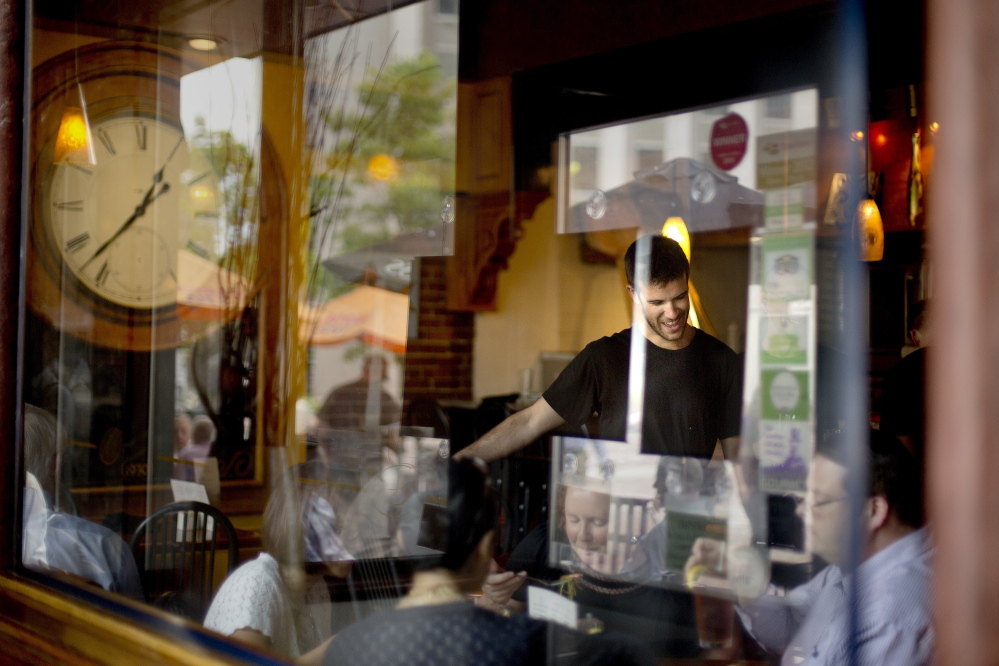 Portland’s Matt Brown, a 26-year-old waiter at David’s Restaurant in Monument Square, serves customers during the lunch rush Thursday. Brown’s perspective on two proposed minimum wage increases in the city offered a striking contrast to most of the food servers and bartenders in Portland’s busy downtown restaurant district: “Getting paid more? I’m all for it,” Brown said.