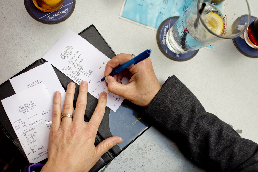 Kim Watson of Scarborough adds a tip after dining with friends at Shay’s Grill Pub in Portland on Thursday. Will increases in the minimum wage affect how patrons tip?