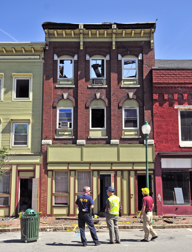 Officials stand in front of the scene the morning after a major fire ripped through downtown Gardiner, where officials hope a rebuilding effort can save the structures.