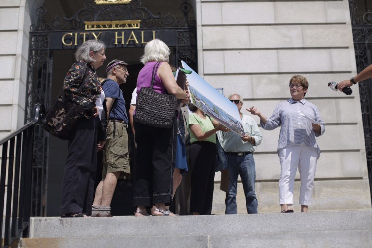 Anne Rand, spokeswoman for the Save the Soul of Portland group, points to waterfront features in a digitally produced image Monday on the steps of City Hall. 
Yoon Byun/Staff Photographer