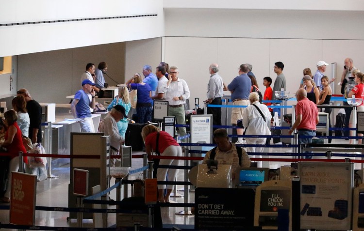 Travelers wait in line Saturday at the Portland International Jetport. Some flights were delayed or canceled due to "technical issues" at an air traffic control center in Virginia.