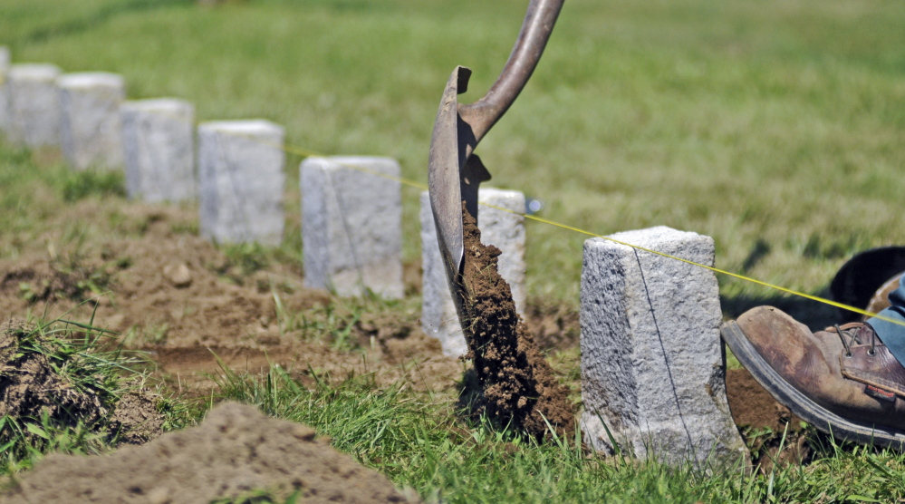 Kevin Miller straightens a row of 4-by-4-inch granite markers Wednesday in one of the soldiers’ lots at Mount Pleasant Cemetery in Augusta.