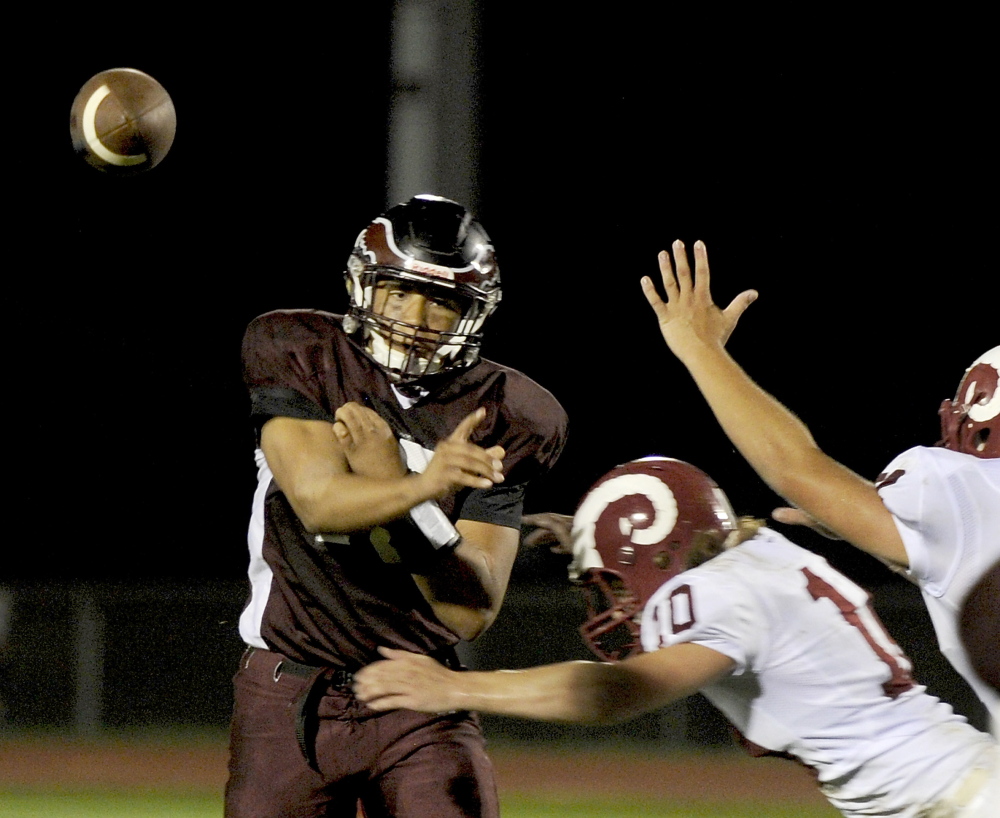Windham quarterback Desmond Leslie throws a pass over Bangor defenders Ben Burt (10) and Mason Hartley. The pass was completed to Kyle Houser.