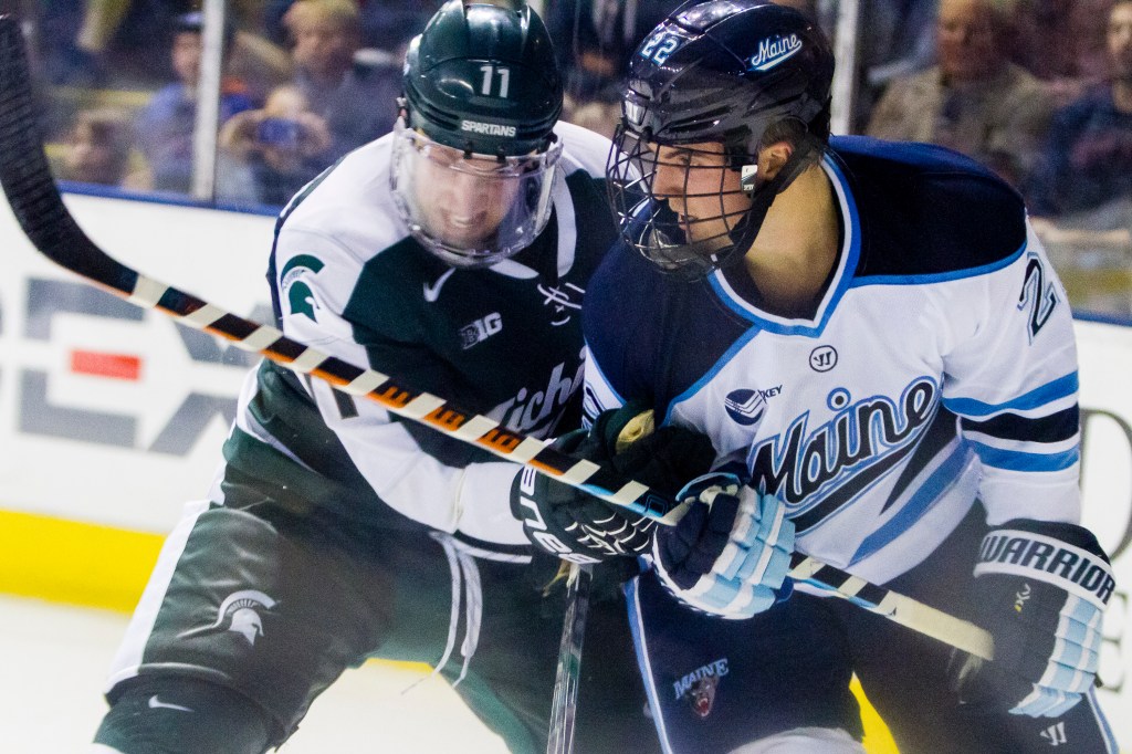 Maine freshman Brendan Robbins fights for the puck with Michigan State's Rhett Holland. Ben McCanna/Staff Photographer