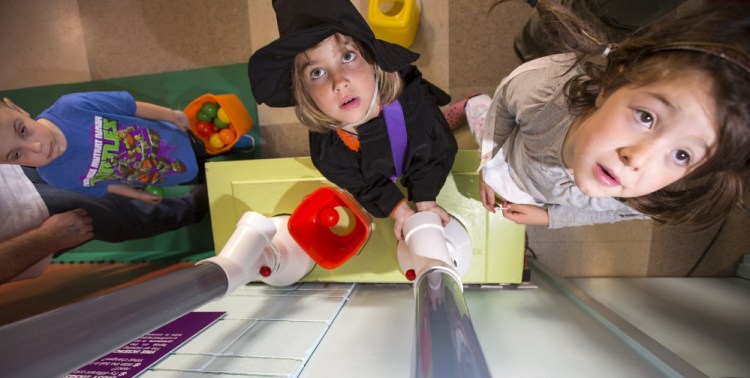 From left, Lewis Walker, Sophie Knoll, and Caroline O’Brien watch Saturday as balls are lifted into pneumatic tubes at the Children’s Museum & Theatre of Maine in Portland.